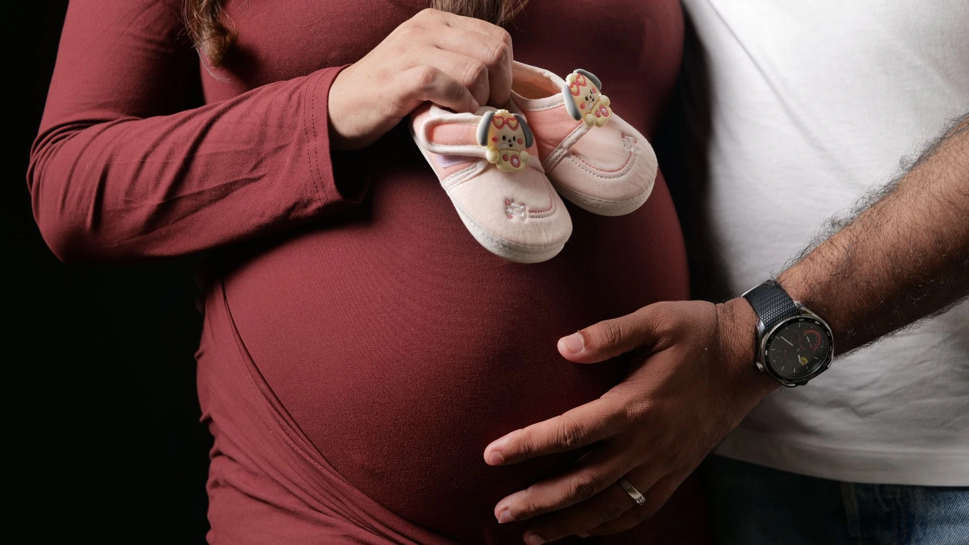 Couple maternity images with tiny baby shoes placed on pregnant belly captured by indo frames