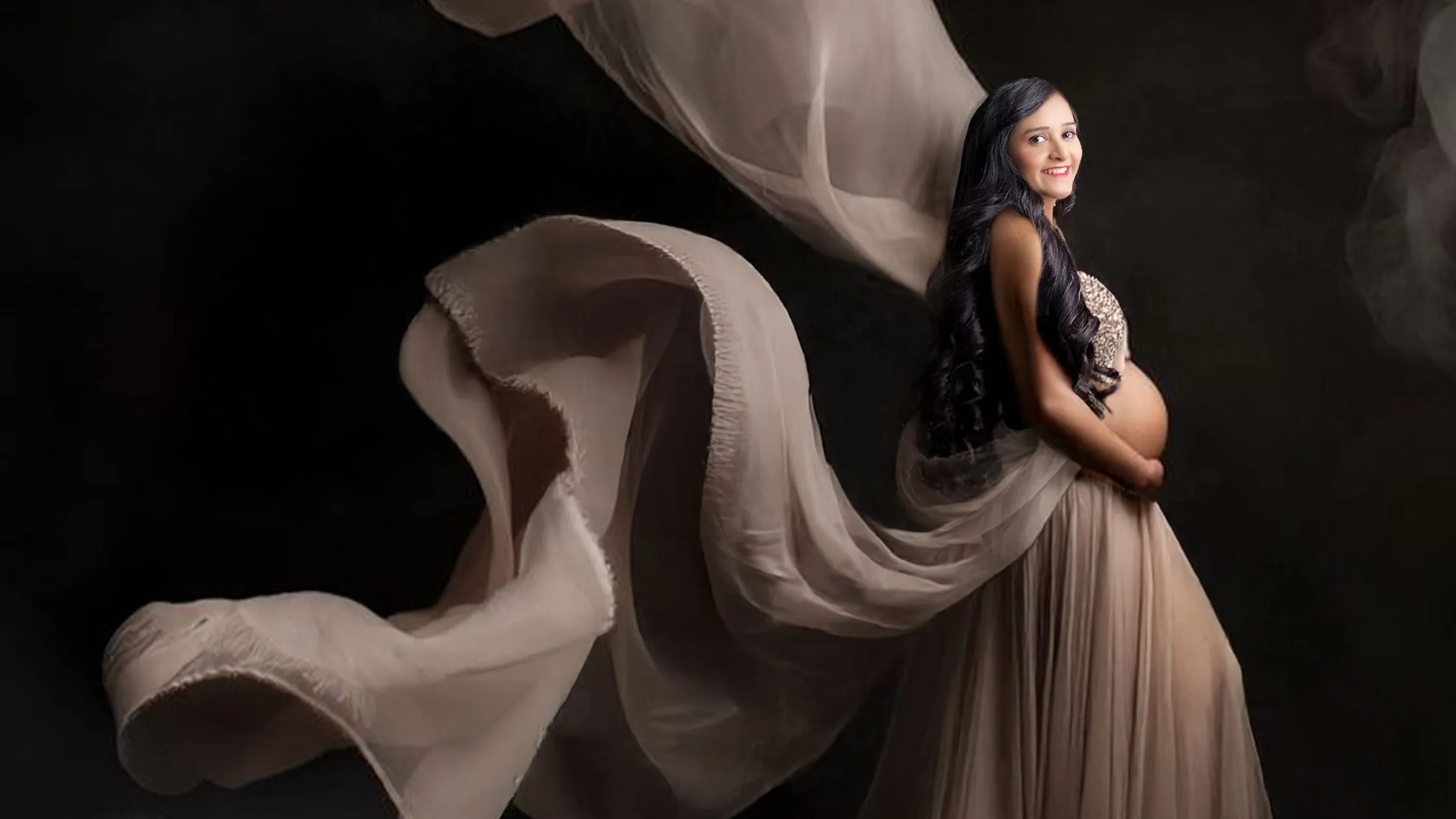 Maternity portrait with flowing fabric and dark artistic background by Indo Frames.