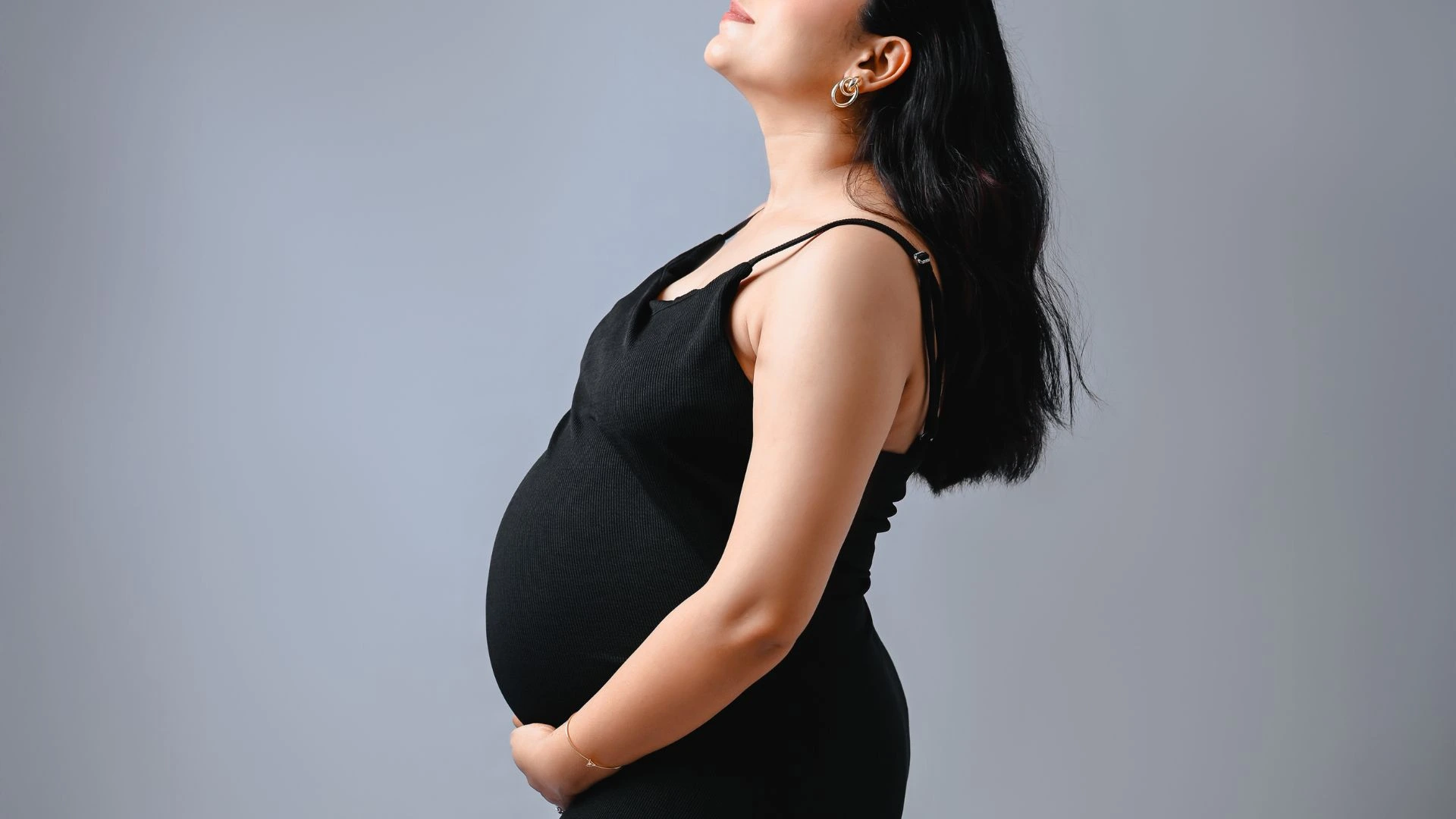 Beautiful maternity images of pregnant woman in black dress side profile pose at Indo Frames studio