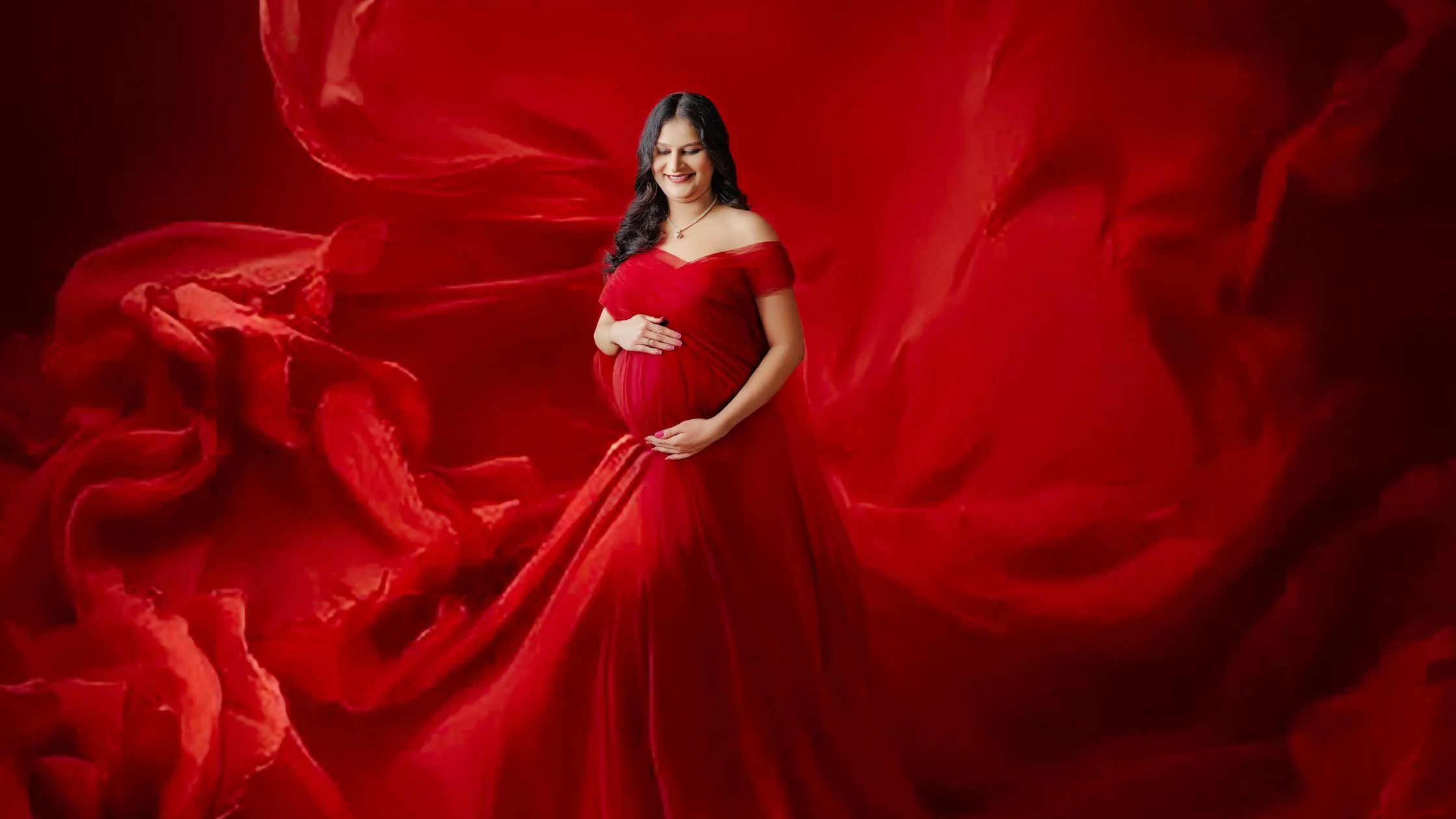 Luxury maternity photoshoot in red gown with creative red floral background by Indo Frames.