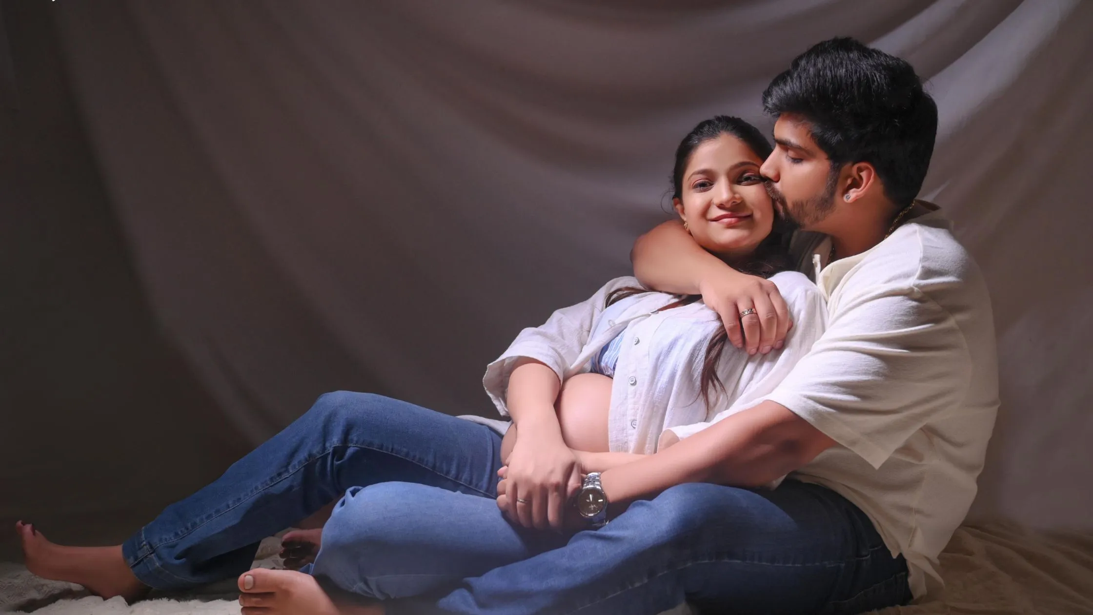 Pregnant couple sitting together during unique maternity photography shoot by indo frames